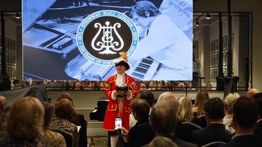 Man in historic attire speaks to an audience at Steinway Hall's 150th anniversary event.