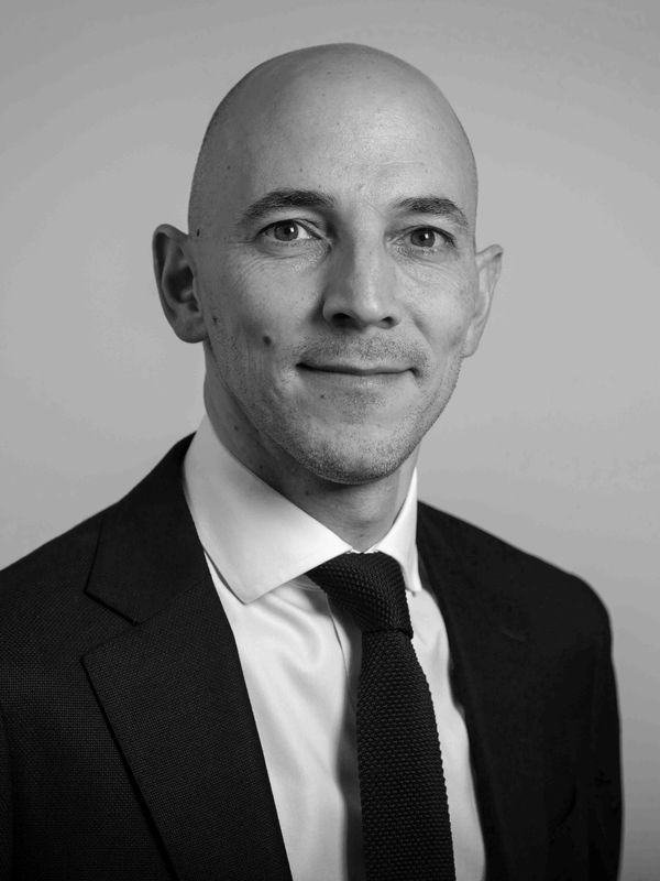Professional black and white portrait of a bald man in a suit and tie.