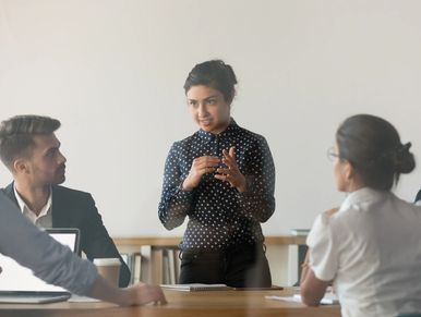Indian female coach meeting booth with diverse work team discuss exchange ideas in conference room