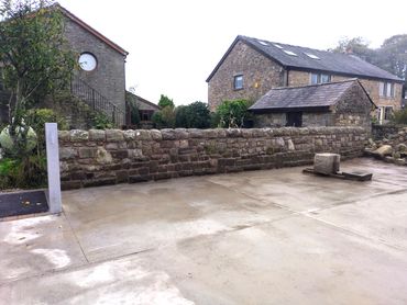 a picture of a mortared stone wall across a stables yard in Manchester