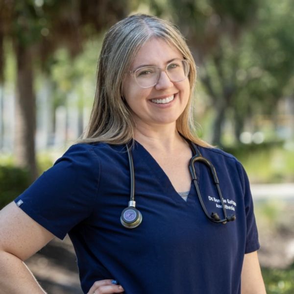 Smiling female doctor in navy scrubs with stethoscope outdoors.