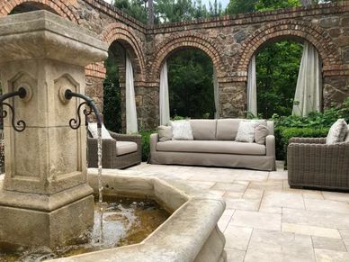Restoration Hardware patio sofa and armchairs in an outdoor patio in front of a fountain.