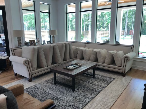 A large cream-colored linen sectional sofa with nail heads in a living room after being cleaned. 