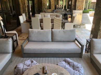 Restoration Hardware outdoor patio sofa in front of an outdoor dining table and eight dining chairs.