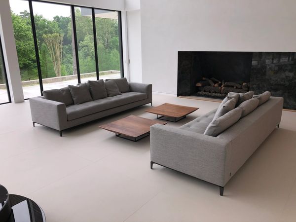 Two gray sofas in front of a fireplace and window wall. Two small square coffee tables.