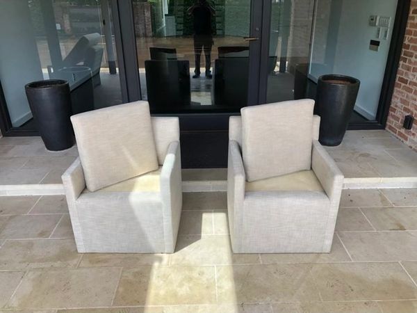 Cream outdoor dining chairs in front of large glass door.