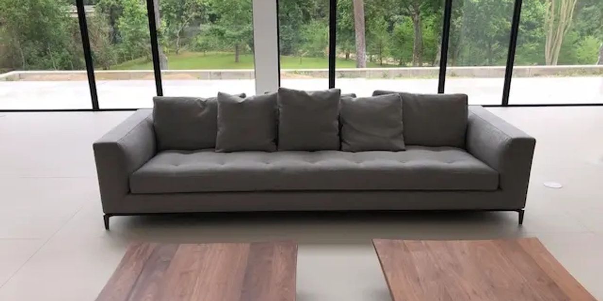 A high-end gray couch sofa in front of a large glass wall after wine stain solvent cleaning.