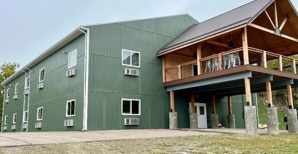 Large green building with multiple air conditioners and a wooden balcony.
