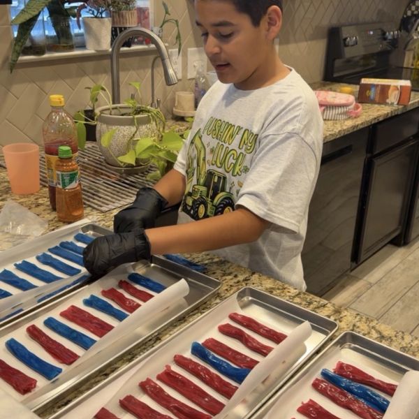 Boy arranging red and blue candy strips on trays.