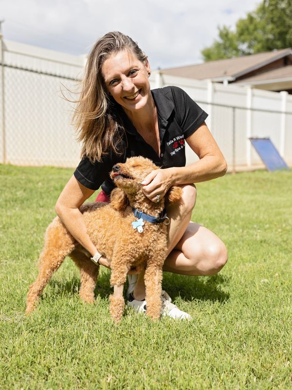 Woman smiling while hugging a dog outdoors.