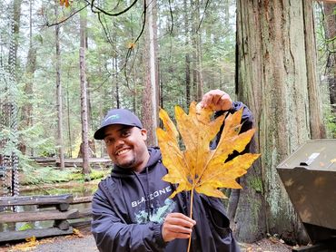 Randy Bowen smiling and holding a maple leaf in Vancouver Canada
