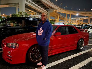 Randy Bowen smiling standing beside a Nissan R34 Skyline.