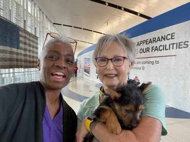 Two women holding fluffy puppy.