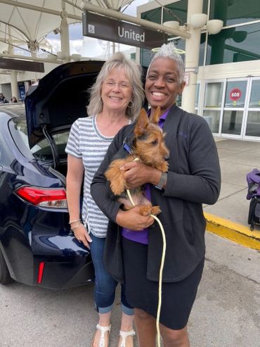 Two women holding brown puppy.
