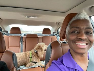 Woman with dog in car.