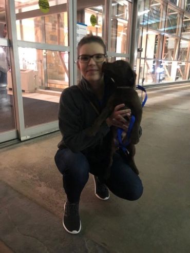 Woman kneeling holding small puppy.
