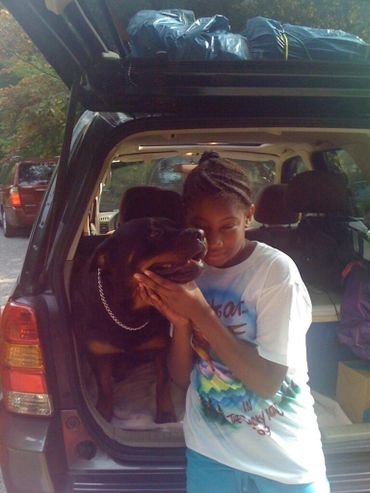 Child hugging dog in car.