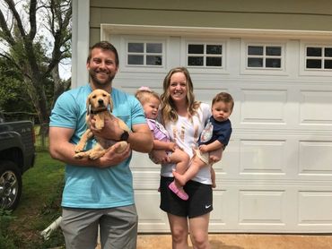Family standing with young dog.