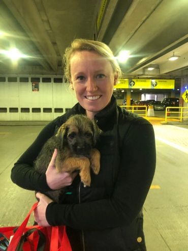 Smiling woman holding brown puppy.