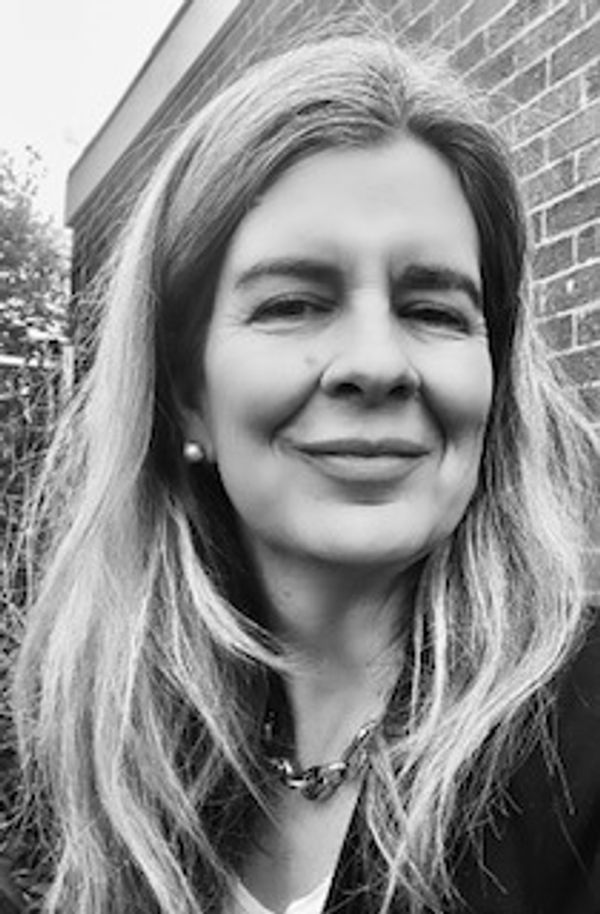 Black and white headshot of PPC founder Candida Tucker-Pierce, with long blond hair and a jacket.