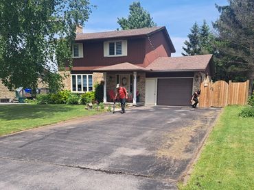 Two people outside a brown two-story house.