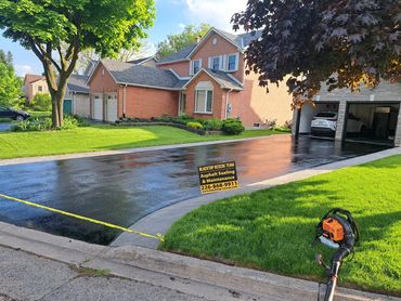 Freshly sealed asphalt driveway at a suburban house.