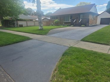A suburban house with a driveway and a green lawn.