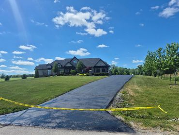 Driveway sealed with caution tape in front of large house.