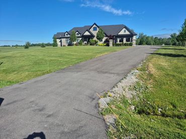 Large house with a paved driveway and green lawn.