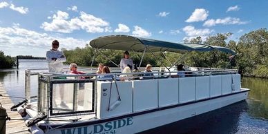A group enjoys a calm boat ride on a sunny day with blue skies and light clouds.