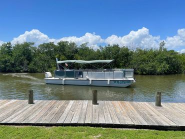 A pontoon boat named Wildside on a calm river with clear skies.