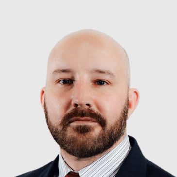 Portrait of a bald man with a beard wearing a suit.