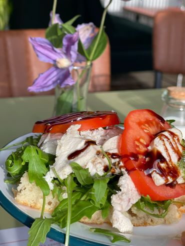 Fresh sandwich with chicken, tomato, arugula, and balsamic glaze.