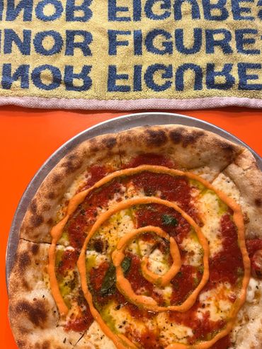 Close-up of a pizza with red sauce swirl on a metal tray.