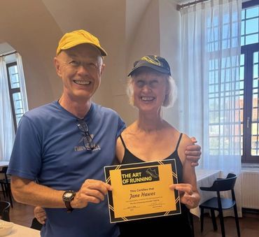 Two happy people holding a running certificate.