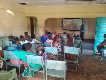 Students attentively watch a lecture in a modest classroom.