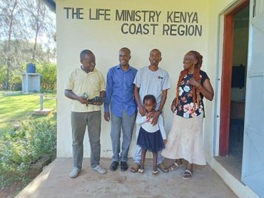Group of five people standing outside The Life Ministry Kenya Coast Region building.