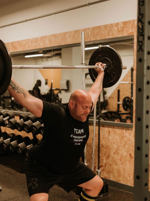 Man lifting a barbell in a gym with intense focus.