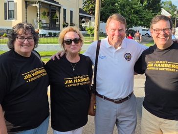 Four people posing outdoors, supporting Jim Hamberger.