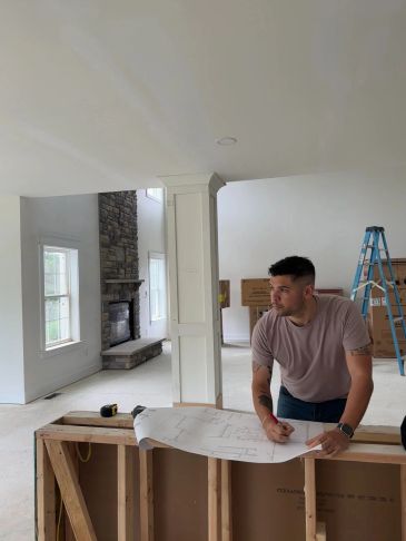 Man reviewing blueprints in unfinished room.