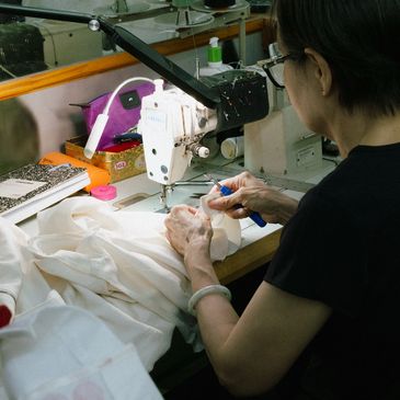 "Tailor at Montague Cleaners making precise adjustments to a white garment at a sewing machine"