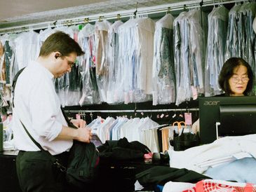 "Wei, owner of Montague Cleaners, assisting a loyal customer—over 5,000 served since 1999"