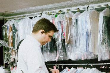 Montague Cleaners staff folding laundry, ironing garments, sewing, and assisting customers inside th