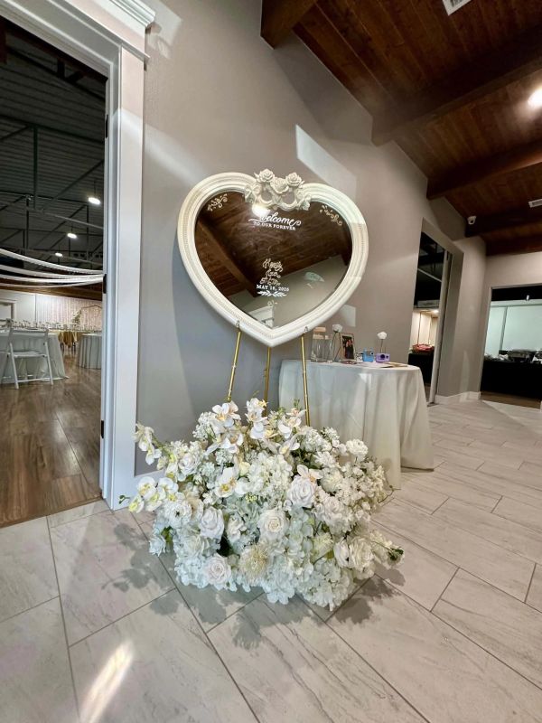 Decorative heart-shaped mirror and wedding floral arrangement in the entry of The Enchanted Point DF
