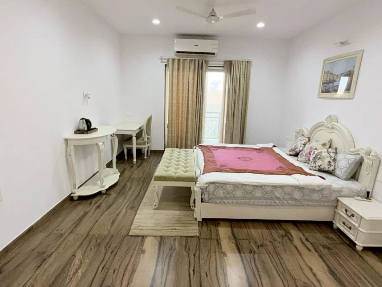 Bright bedroom with elegant white furniture and wooden flooring.