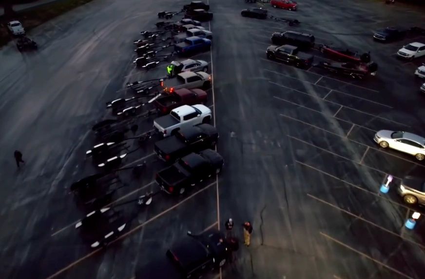 Aerial view of parked trucks and trailers in a large parking lot at dusk.