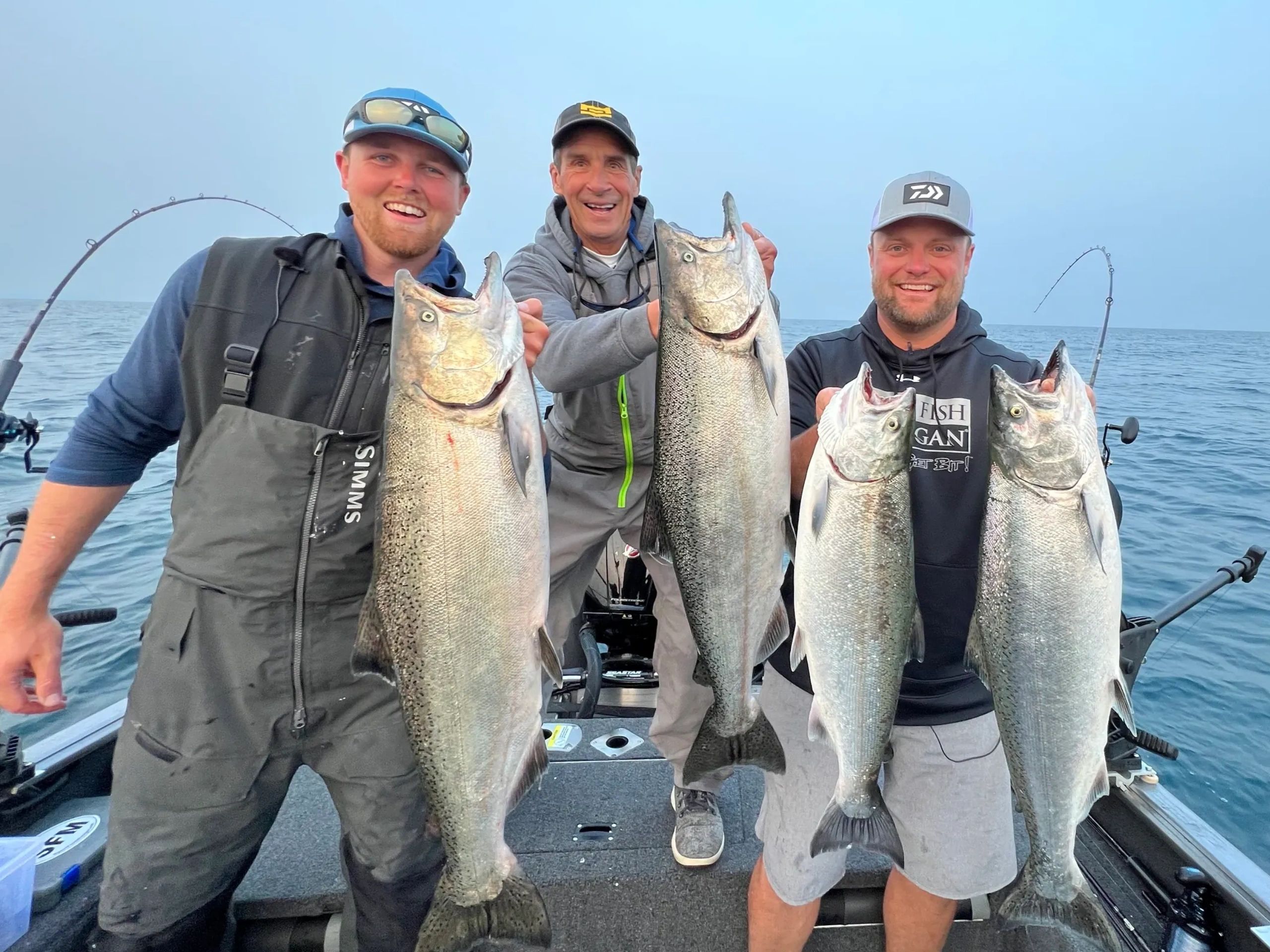 Three men in baseball hats holding three large fish