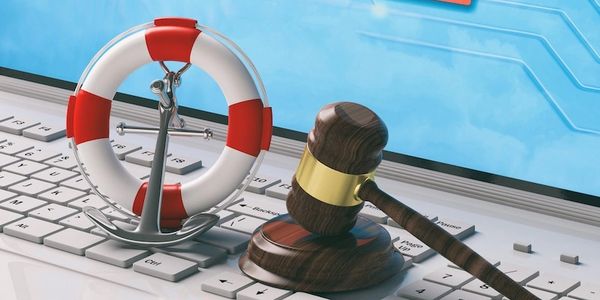 Gavel, anchor, and lifebuoy on a keyboard symbolizing legal protection in maritime or cyber law.