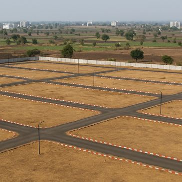 Empty plot layout with paved roads and streetlights under a clear sky.