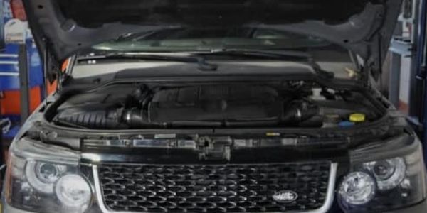 Open hood of a Land Rover vehicle showing the engine compartment.